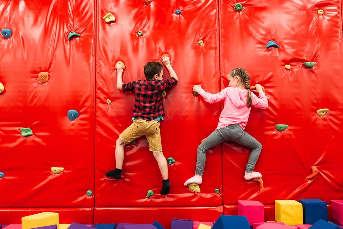 Active kids climbing on a wall in childrens attraction playground. Entertainment center. Happy childhood