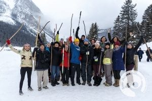 Group of people standing outdoors, raising sticks in the air and smiling