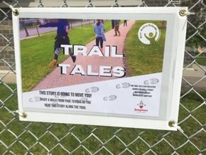 A laminated, corrugated plastic board with an image on it that says "Trail Tales". This is the introductory page to inform passersby of the purpose of the Trail Tales project.