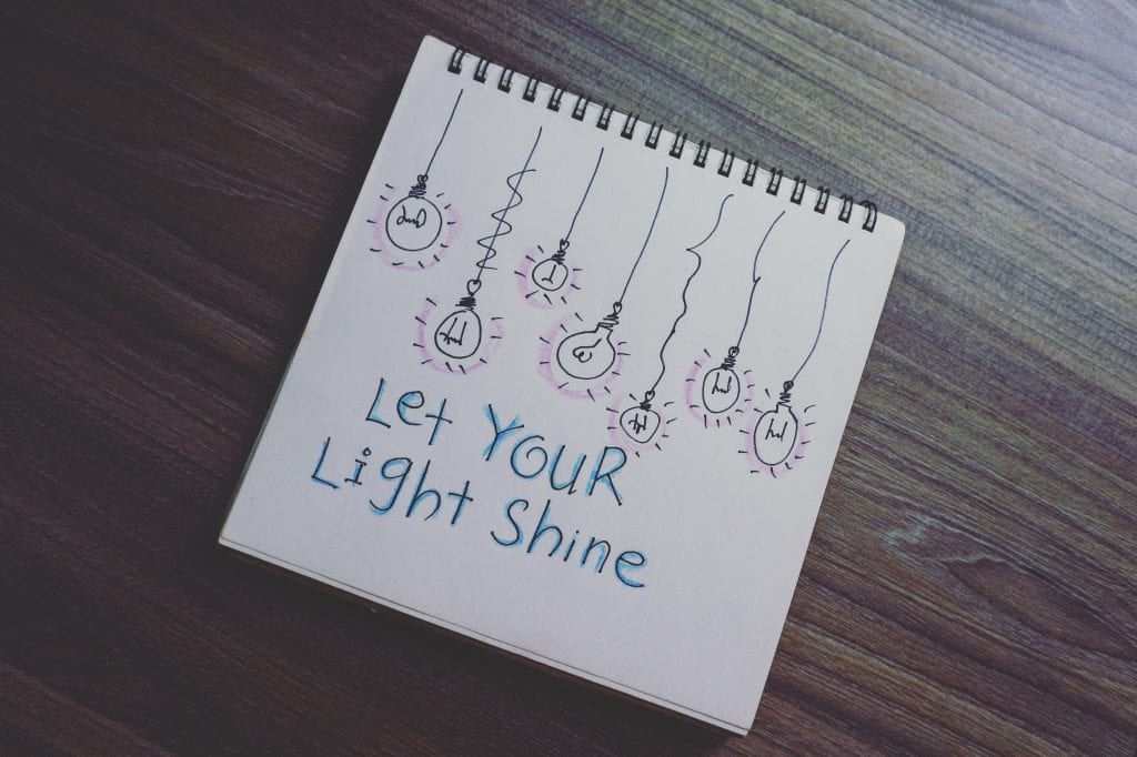 A drawing of black lightbulbs with purple flashes, and blue text below: "Let Your Light Shine"
