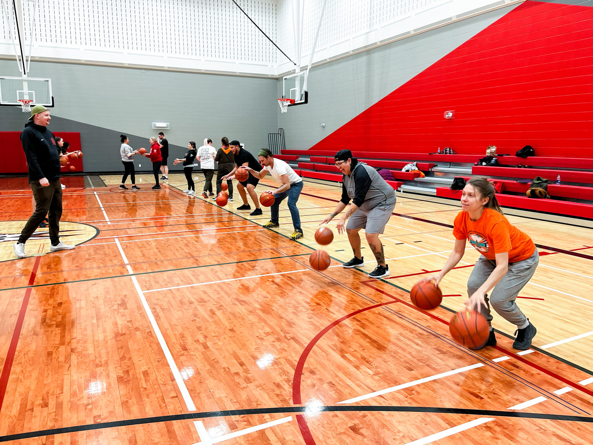 A line of adults dribble two basketballs each. Taken during an Everybody Plays Leagues of Play coaching clinic.