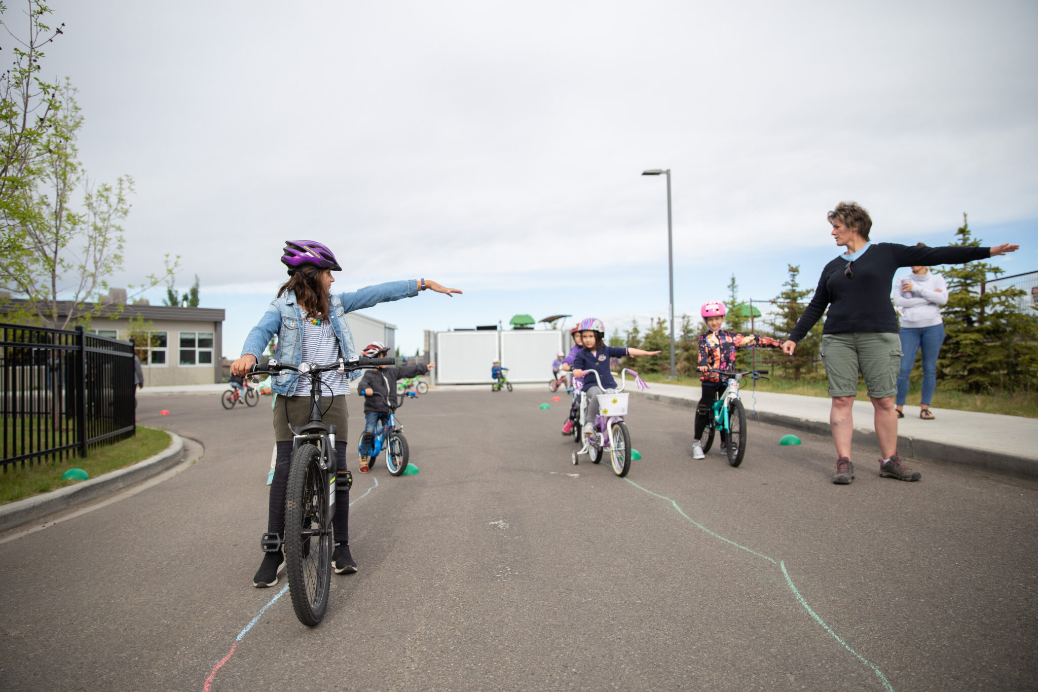 A group of children on bikes practices signalling a left turn with their arms.