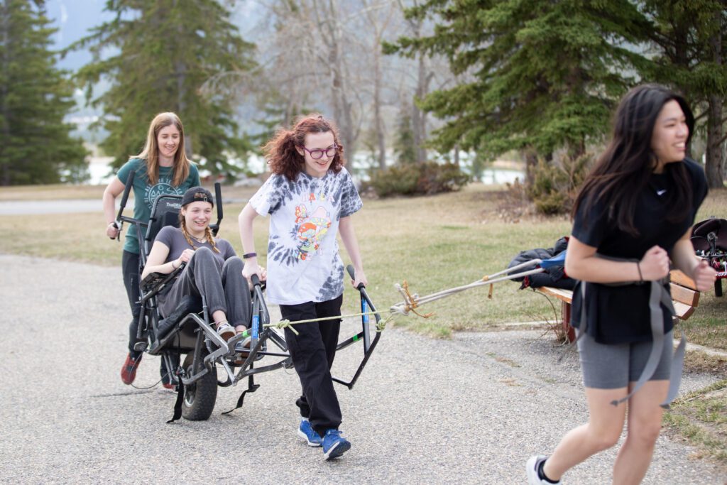 Recreation Leadership students pulling another student in a sit down bicycle